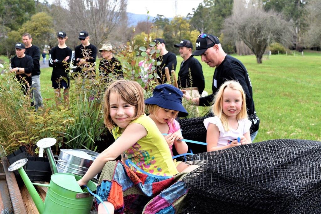 Photo of children and corporate volunteers helping to plant trees.